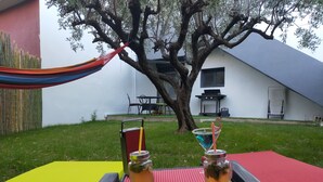 Eine Terrasse mit einer Hängematte, einem Tisch mit Getränken und einem Baum.