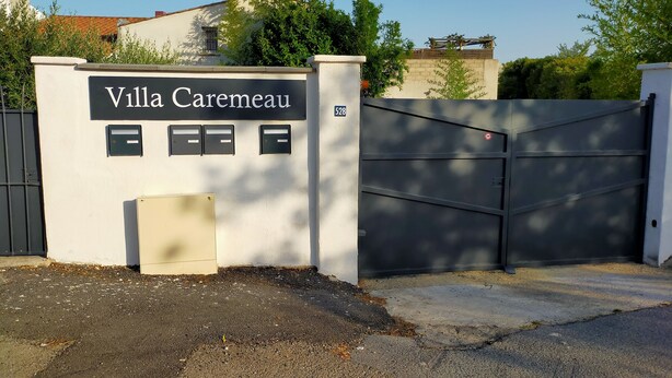 Ein begrenzter Zugang zur Villa Caremeau mit einem Schild, einem Briefkasten und einem Hausnummernschild.