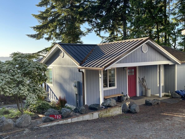 A single-story house with a red door, a covered porch, and a metal roof.