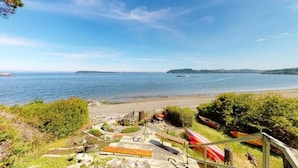 A coastal view with a beach, kayaks, and a clear sky.