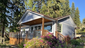 A two-story house with a covered porch, large windows, and a wooden deck.
