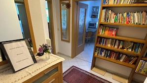 A reception area with a desk, a welcome sign, a bookshelf, and a view into a dining area. - Baiersbronn, Black Forest, Schwarzwald, view, 2 rooms, sun, balcony, quietness (Baiersbronn)
