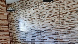 Un espace douche avec un mur à texture et un luminaire fixé au plafond.