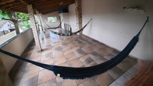 Une pièce spacieuse avec un sol carrelé, un hamac et un pilier en pierre.