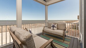 A covered outdoor seating area with a view of the beach and ocean.