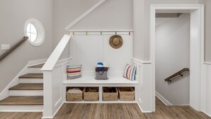 A staircase with a bench at the top, baskets below, and a hat hanging on the wall.