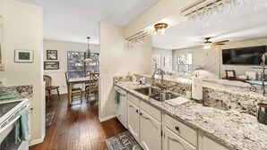 A kitchen with granite countertops, white cabinetry, a built-in oven, and a dining area with a wooden table and chairs. - Gertie’s Getaway Mountain Retreat Family Friendly  Couples Weekend (Ruidoso)
