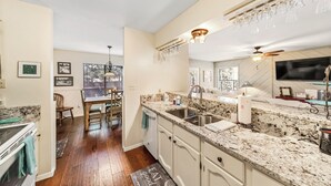 A kitchen with granite countertops, white cabinetry, a built-in oven, and a dining area with a wooden table and chairs. - Gertie’s Getaway Mountain Retreat Family Friendly  Couples Weekend (Ruidoso)