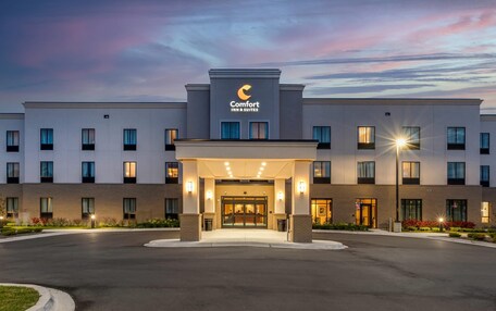 A hotel entrance with a covered entryway, multiple windows, and a clear sky.