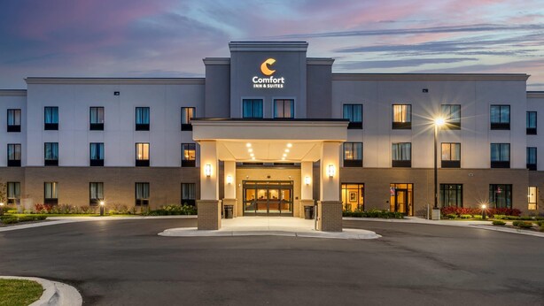 A hotel entrance with a covered entryway, multiple windows, and a clear sky. - Comfort Inn & Suites Clarkston Pine Knob Area (Clarkston)