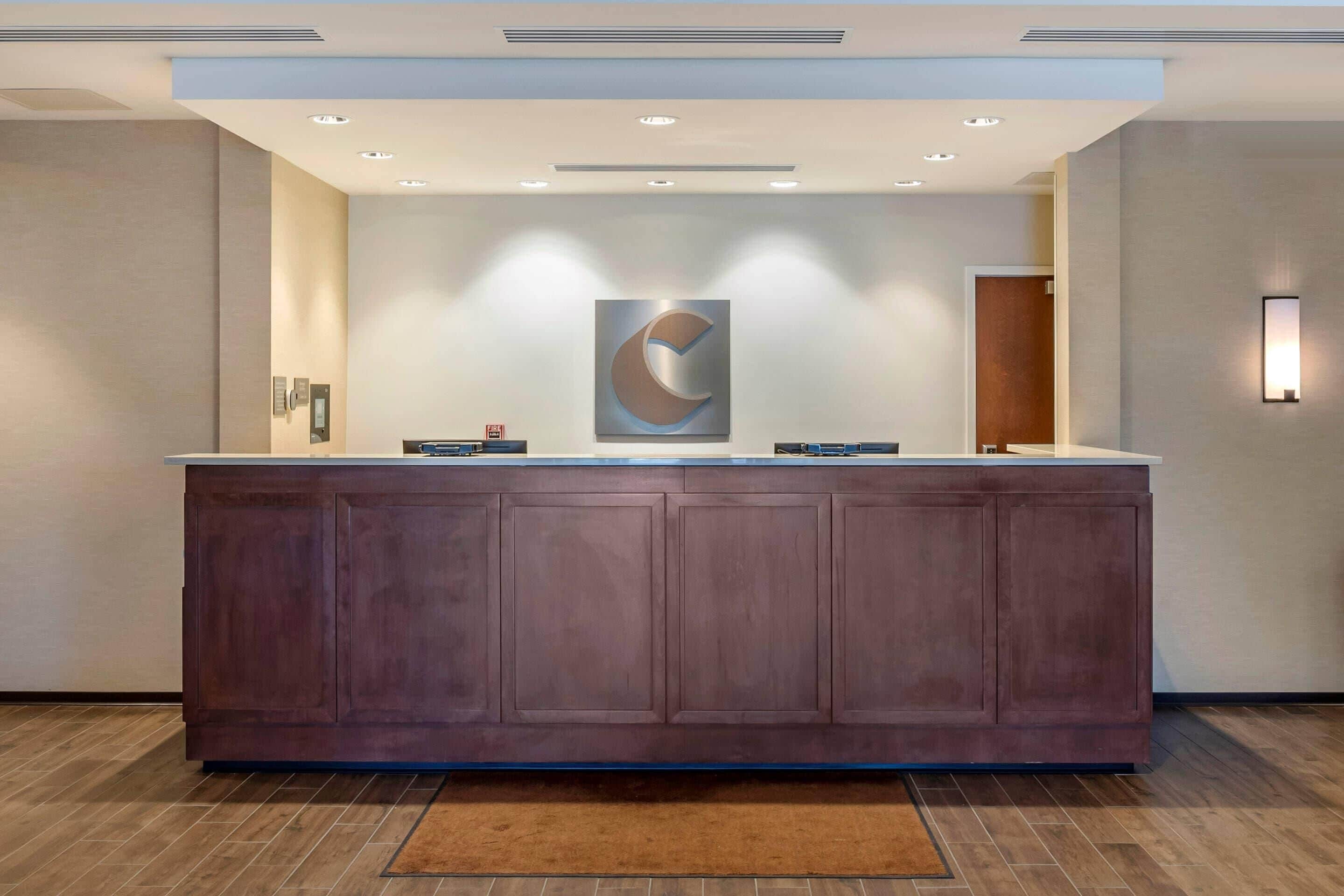 A reception desk with a modern design, recessed lighting, and a large abstract wall art piece.