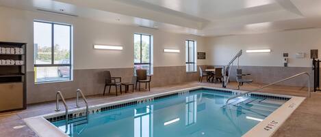 A swimming pool with clear markings, a sunlit room with a view, and a reception area with chairs and a counter.