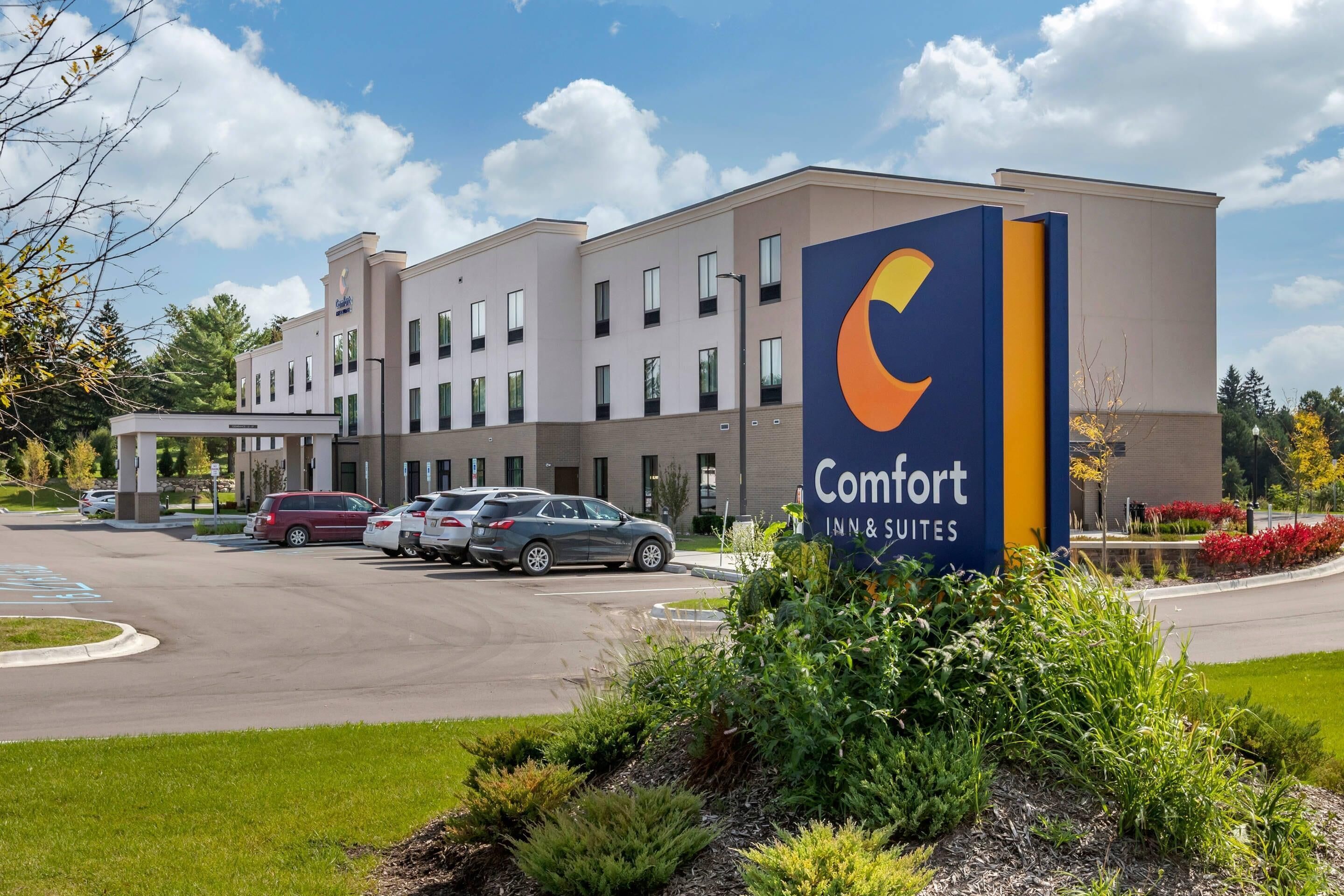 Un hotel amb un rètol que diu 'Comfort Inn & Suites', que presenta un edifici modern amb nombroses finestres i un aparcament.