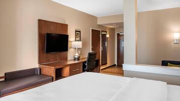 Une chambre d’hôtel avec un lit, un bureau, une chaise, une télévision et une porte.