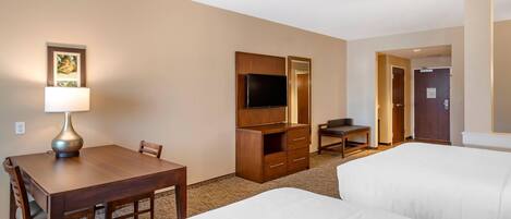 A hotel room with a bed, a desk with a lamp, a TV, and a wardrobe.