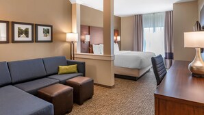 A hotel room with a bed, a desk, a sofa, and a small table. - Comfort Inn & Suites Clarkston Pine Knob Area (Clarkston)
