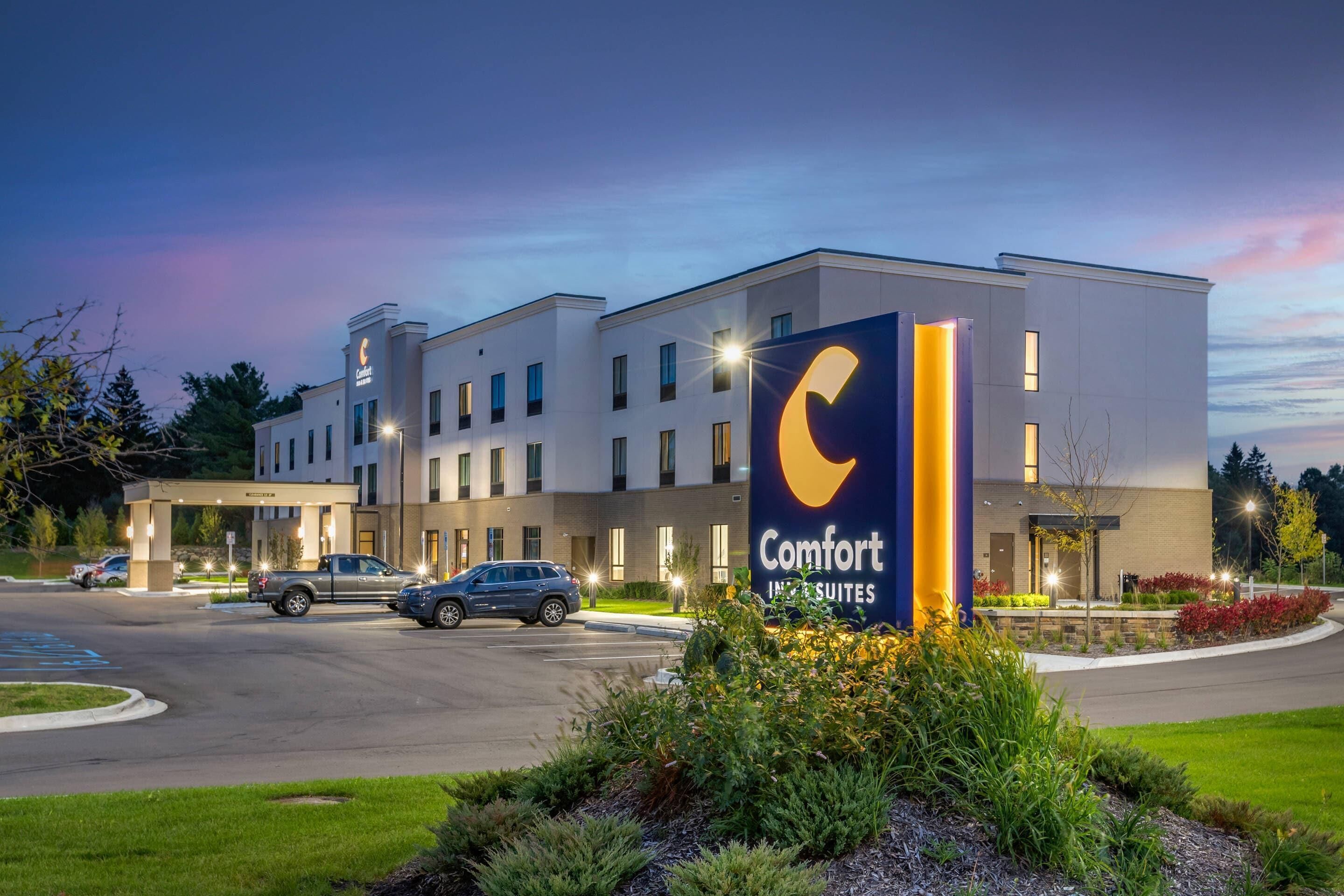 A Comfort Suites hotel with a modern design, a parking lot, and a well-lit entrance.