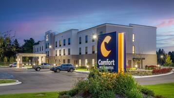 A Comfort Suites hotel with a modern design, a parking lot, and a well-lit entrance.
