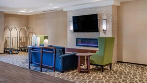 A hotel lobby with a sofa, chairs, a flat-screen TV, a fireplace, and luggage carts. - Comfort Inn & Suites Clarkston Pine Knob Area (Clarkston)