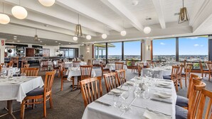 A restaurant with multiple dining tables, chairs, and hanging pendant lights. - Comfort Inn The Lakes (Mount Gambier)