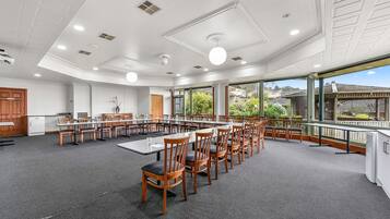 A conference room with a long table and chairs, large windows, and a view of the outdoors.