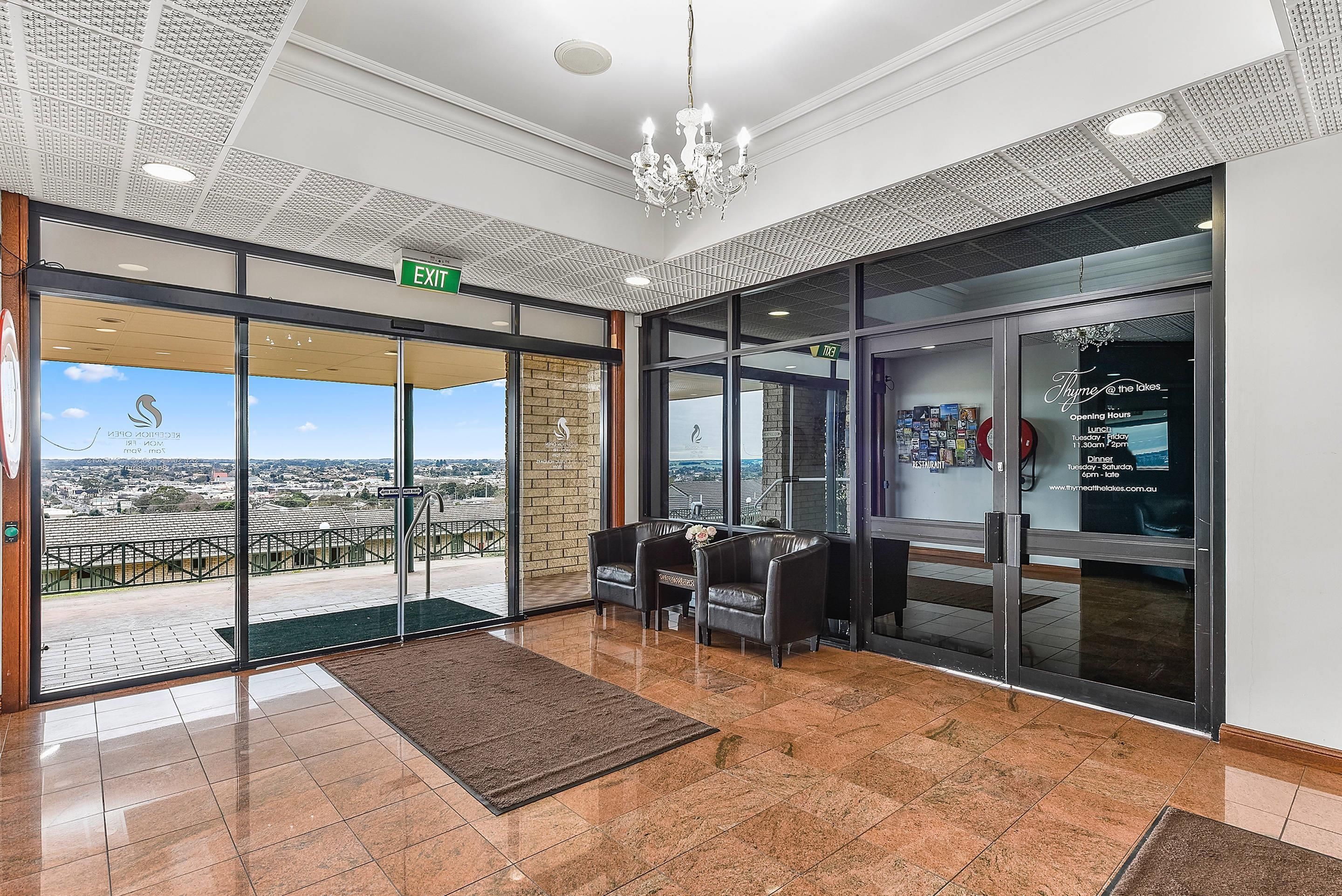 A hotel lobby with a view of the city, a reception desk, and a chandelier.