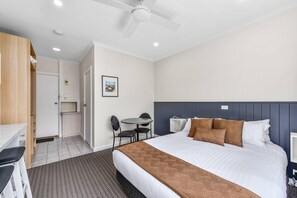 A hotel room with a bed, bedside table, a desk with a chair, a small kitchenette, and a ceiling fan. - Comfort Inn The Lakes (Mount Gambier)