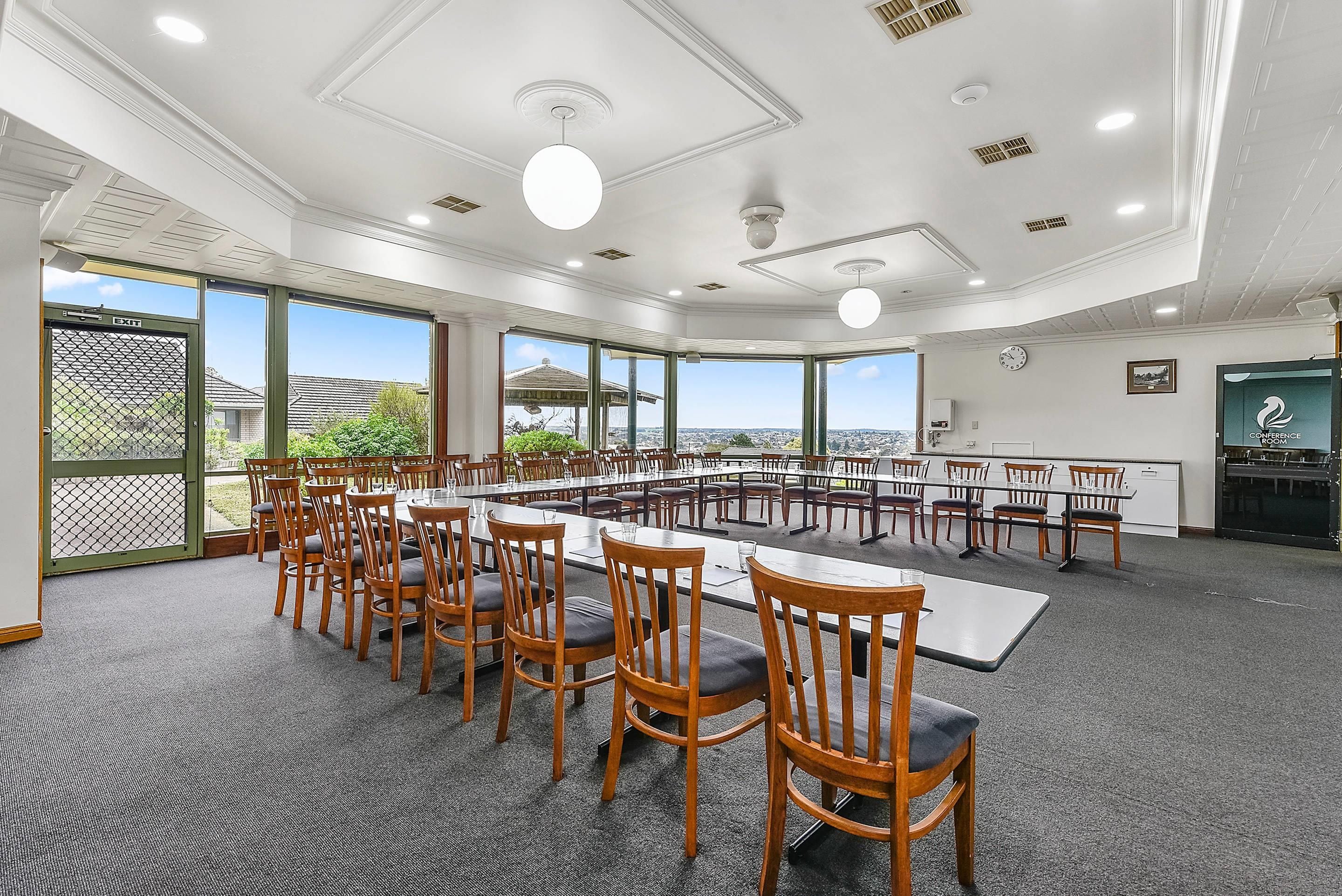 A conference room with a long table, multiple chairs, and large windows offering a view.