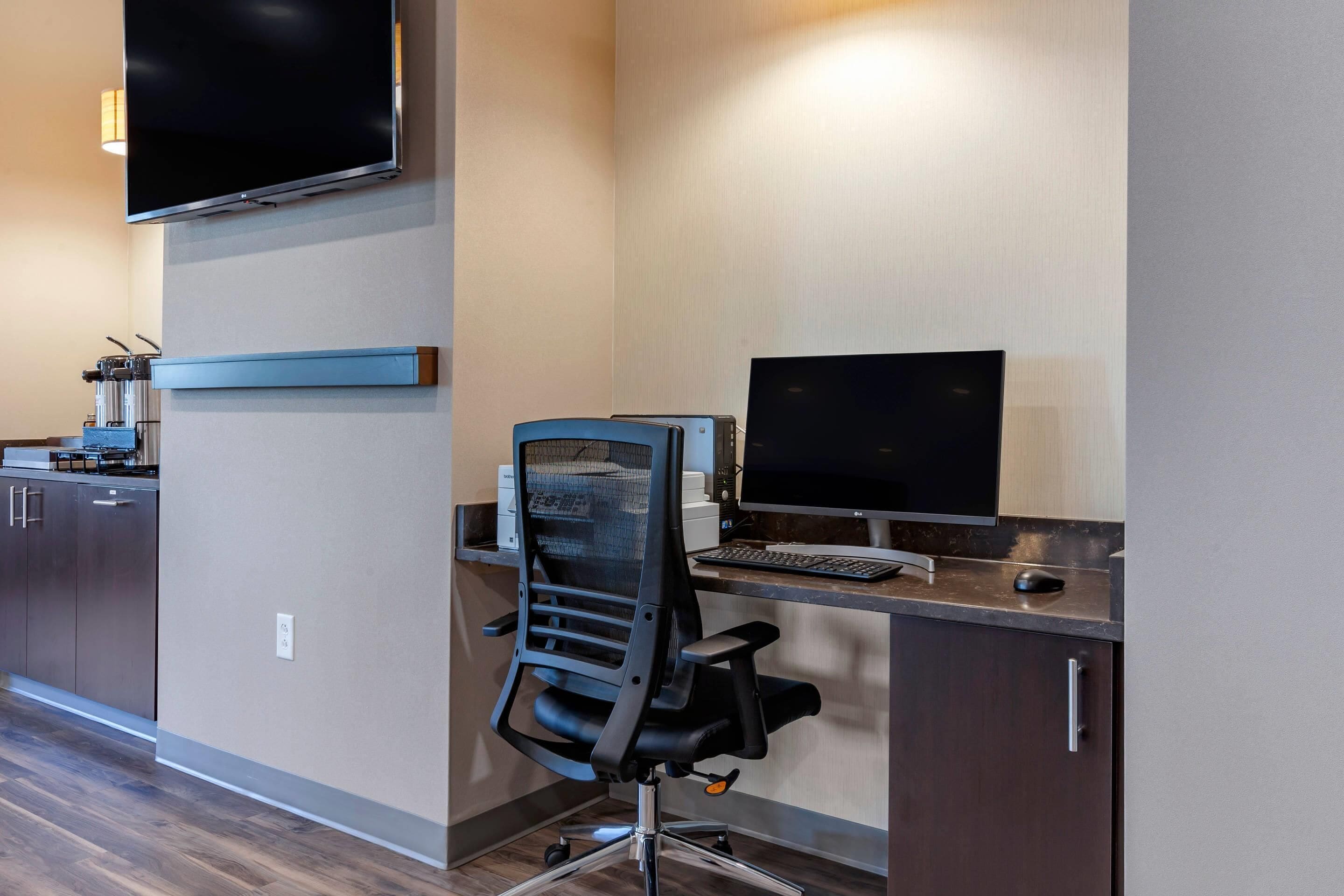 A modern office space with a desk, computer, chair, and a flat-screen monitor.