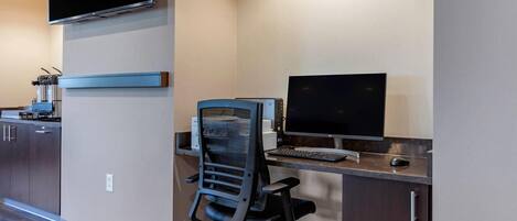 A modern office space with a desk, computer, chair, and a flat-screen monitor.