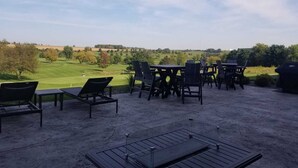 En uteplats med sittplatser och utsikt över en golfbana.