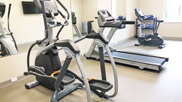 A gym with treadmills, an elliptical, and a mirrored wall.