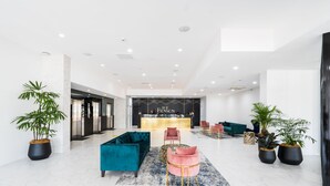 A modern lobby with a reception desk, plush seating, and potted plants. - The Benson Hotel (Cairns)
