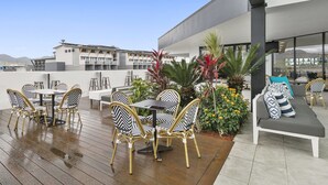 A rooftop patio with outdoor furniture, a dining table, and a sofa. - The Benson Hotel (Cairns)