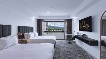 Ein Hotelzimmer mit zwei Betten, einem Schreibtisch, einem Stuhl, einem Fernseher und Bergblick.