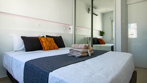 A neatly made bed with a blue blanket, white pillows, and a folded towel on a white bedspread. - Phaedrus Living: Seaside Luxury Flat Lighthouse 65 (Paphos)