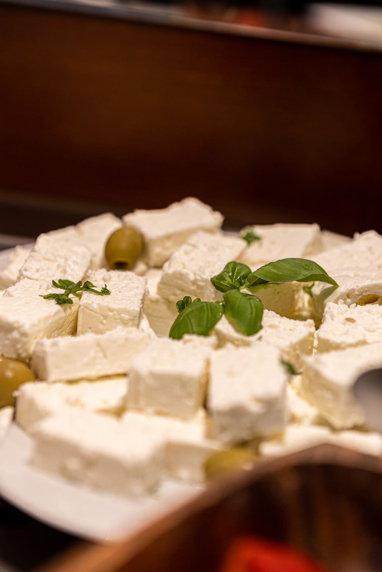A plate of cubed cheese garnished with green leaves.