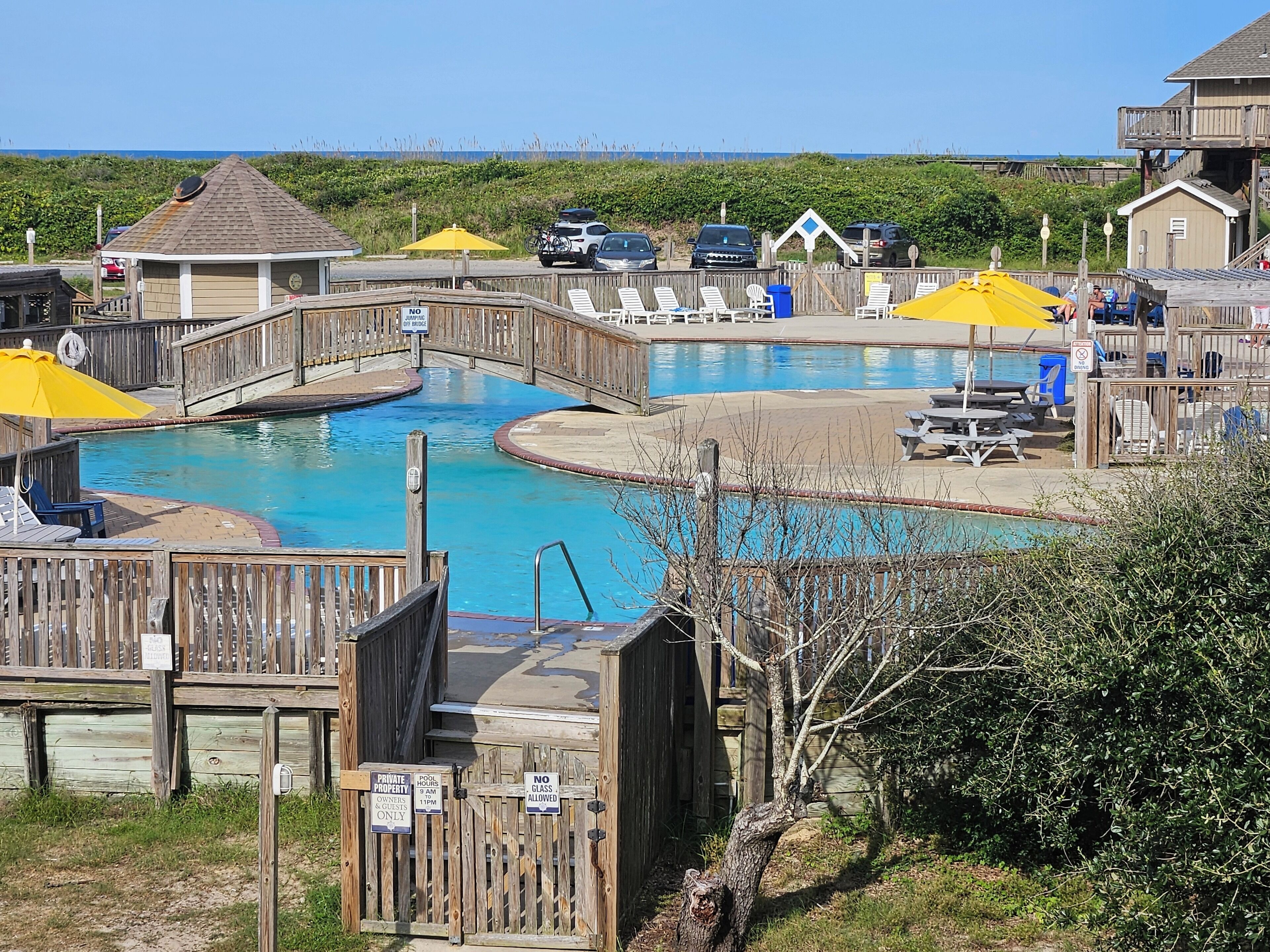 A wooden deck with a pool, a wooden bridge, and a sign indicating private property for owners and guests only.