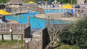 A wooden deck with a pool, a wooden bridge, and a sign indicating private property for owners and guests only. - Condo located in Barrier Island Station Duck Resort Unit 505A (Duck)