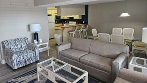 A living room with a sofa, armchairs, a glass coffee table, and a ceiling fan. - Condo located in Barrier Island Station Duck Resort Unit 505A (Duck)