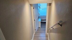 A wooden staircase with white trim leading to a bedroom with a bed and a window. - Condo located in Barrier Island Station Duck Resort Unit 505A (Duck)