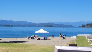 A lakeside view with a white tent, boats, and mountains in the background. - Wooded, peaceful setting 15 minutes from  the Lake! (Sandpoint)