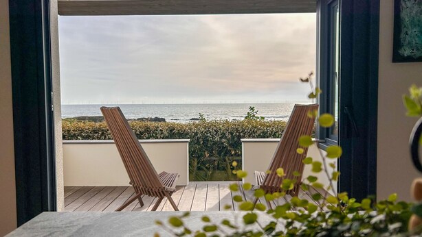 A balcony with two wooden chairs, a view of the sea, and a plant in the foreground. - Maison Avec Vue Panoramique sur L'océan (BATZ SUR MER)