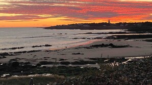 A coastal landscape with a rocky shoreline, calm sea, and a sunset with vibrant colors. - Maison Avec Vue Panoramique sur L'océan (BATZ SUR MER)