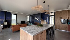 A modern kitchen with a marble island, wooden accents, and pendant lighting. - Maison Avec Vue Panoramique sur L'océan (BATZ SUR MER)