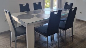 A dining area with a white table and black chairs, a view of the sea through a window, and a curtain. - Apartment Maya 1 (Marušici)