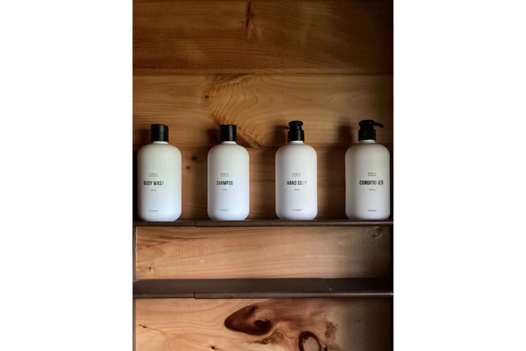 Four bottles of personal care products on a wooden shelf.