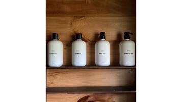 Four bottles of personal care products on a wooden shelf.