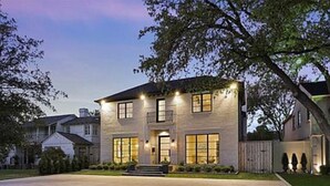 Une maison à deux étages avec une allée, une pelouse et un arbre.