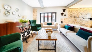 A modern living room with a stone wall, a wooden coffee table, a sofa, and a green armchair.